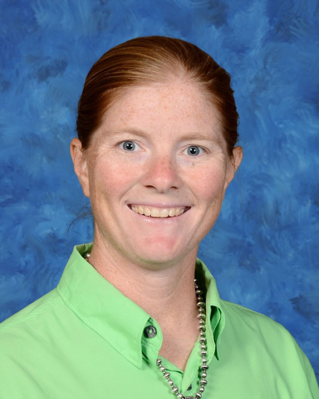 picture of a teacher with a big smile wearing a green shirt